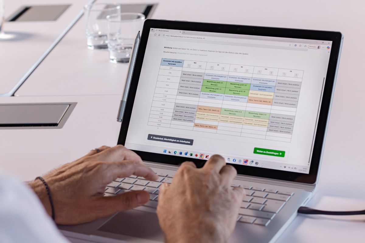 Person tippt auf einem Laptop, auf dem Bildschirm ist eine Tabelle zu sehen