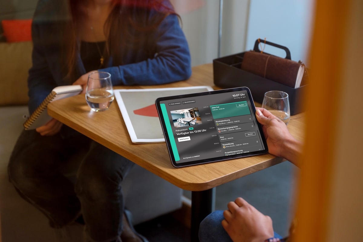 Person hält ein iPad in der Hand auf dem die Desk-Sharing-Software deskbird zu sehen ist