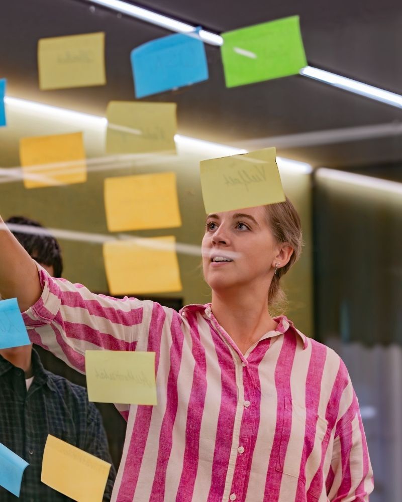 Mitarbeiterin platziert Post-Its im Zuge des Workspace Analytic Prozesses zur Bedarfsermittlung von designfunktion