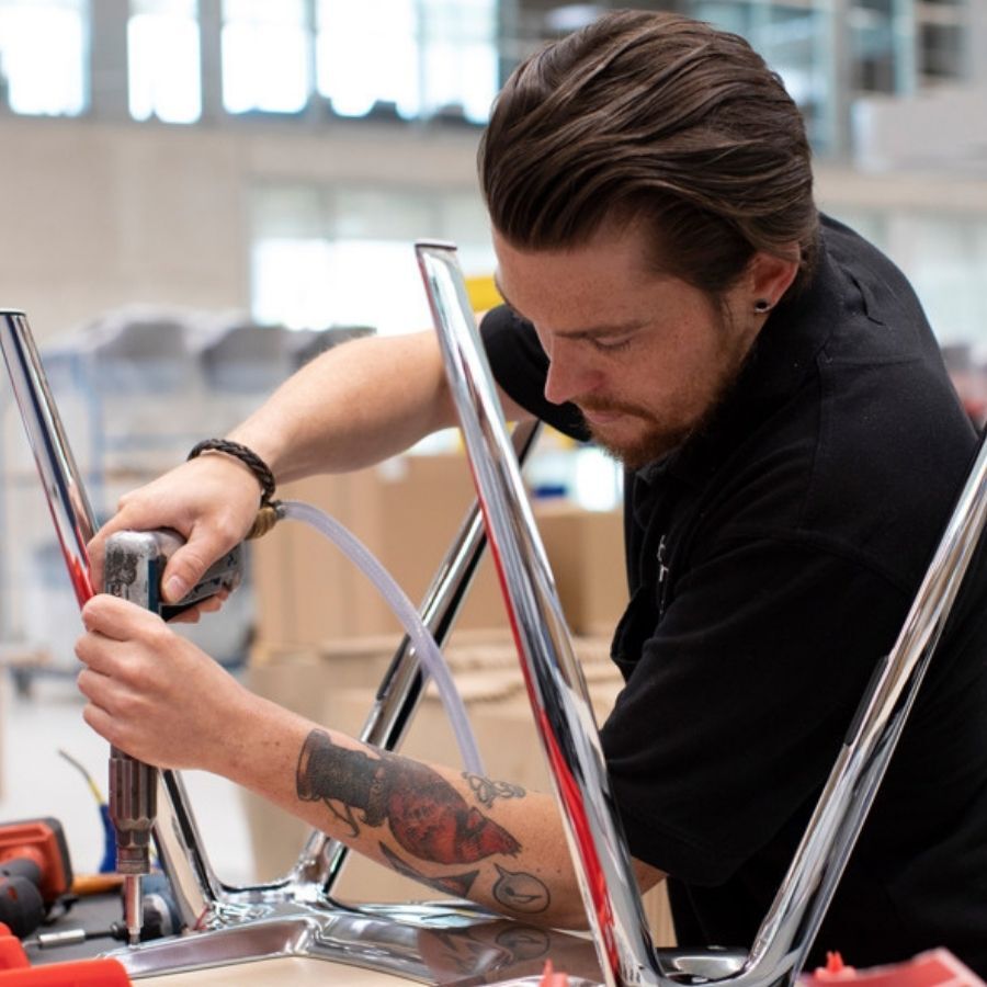 Mitarbeiter beim Befestigen eines Untergestells an der Sitzschale eines Stuhls bei Brunner