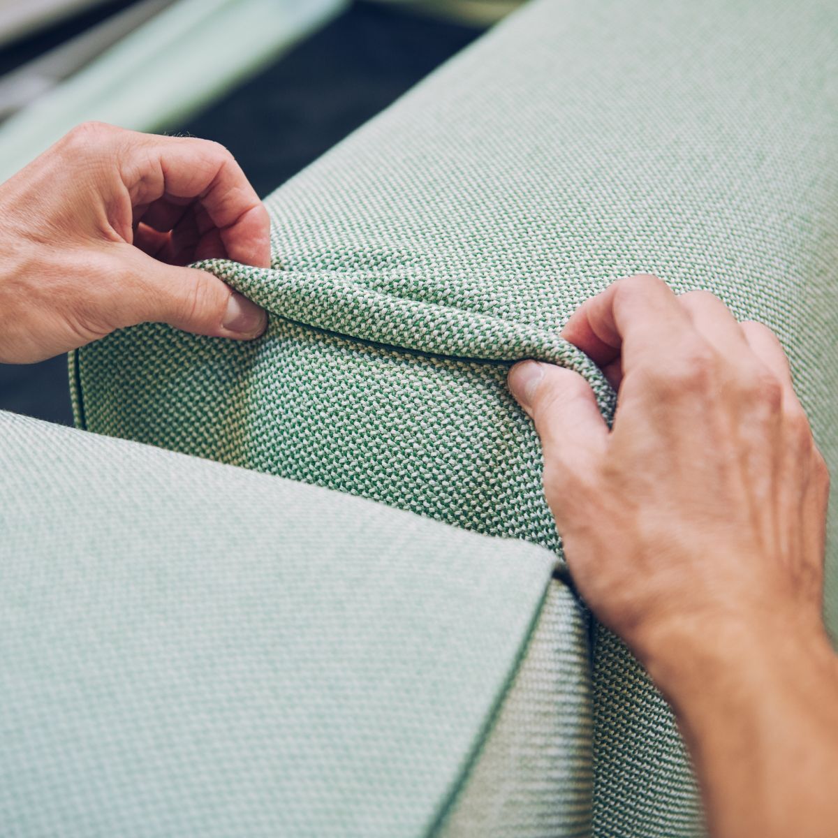 Mitarbeiter von COR zieht den Bezug an einem Möbelstück in die richtige Position