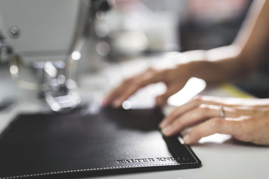 Hände auf Tisch und in Leder geprägtes Logo von Walter Knoll