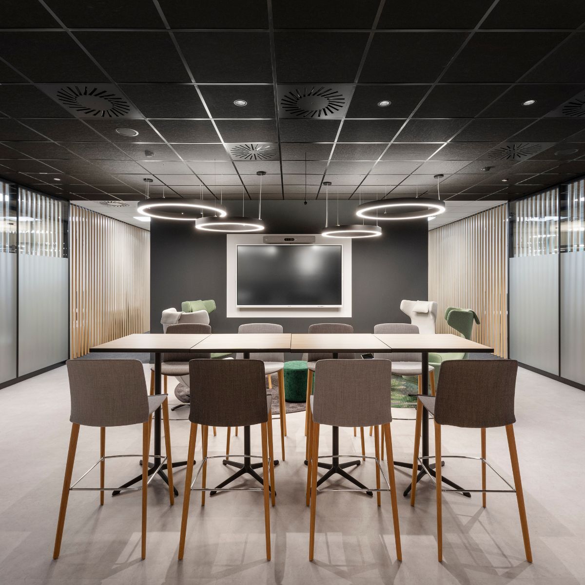 Gemeinschaftsbereich mit Hochtisch und Stühlen im Vordergrund in der Arbeitswelt von Advantest am Standort München, geplant und eingerichtet von designfunktion