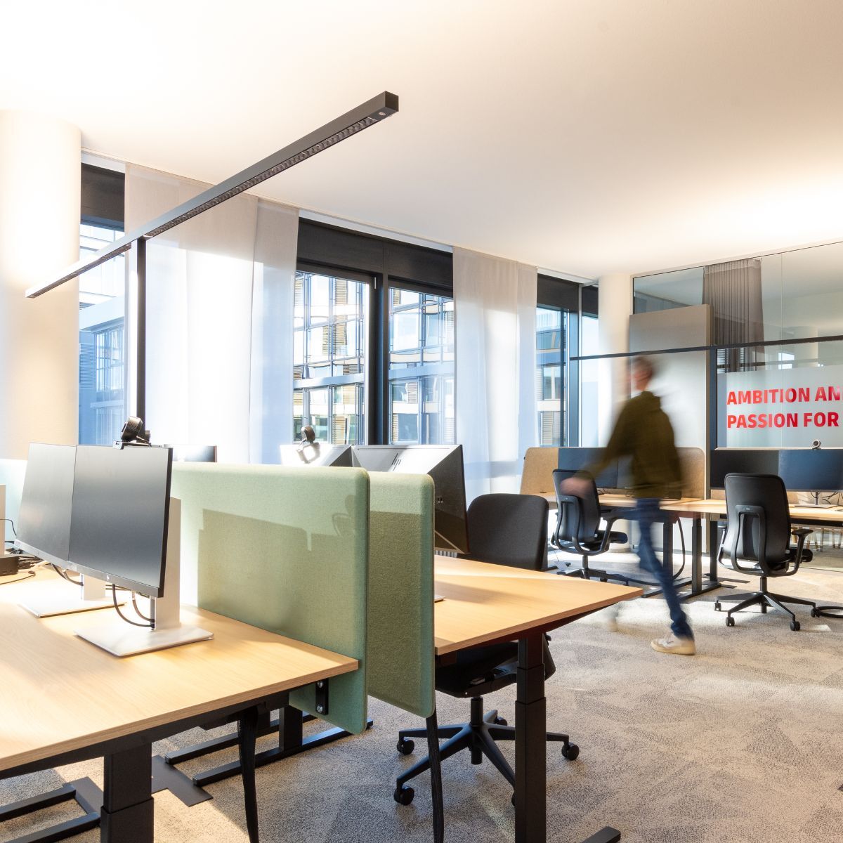 Einzelarbeitsplätze vor großen Fenstern in der neuen Arbeitswelt von DHL Supply Chain EMEA, geplant und eingerichtet von designfunktion