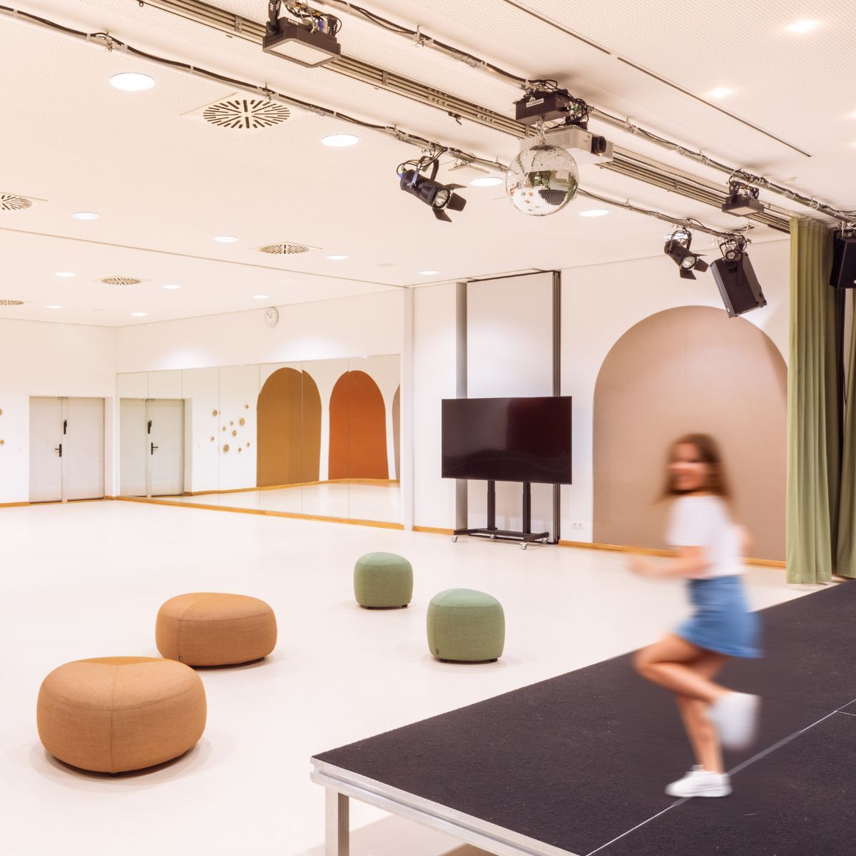 Mädchen auf der Bühne des Gemeinschaftsraums der Frankfurt International Primary School in Oberursel, geplant und eingerichtet von designfunktion