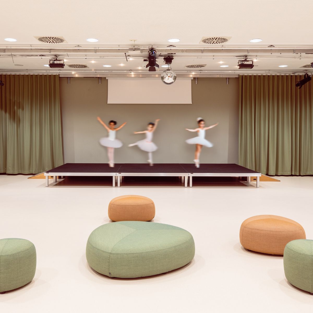Kinder auf der Bühne des Gemeinschaftsraums der Frankfurt International Primary School in Oberursel, geplant und eingerichtet von designfunktion
