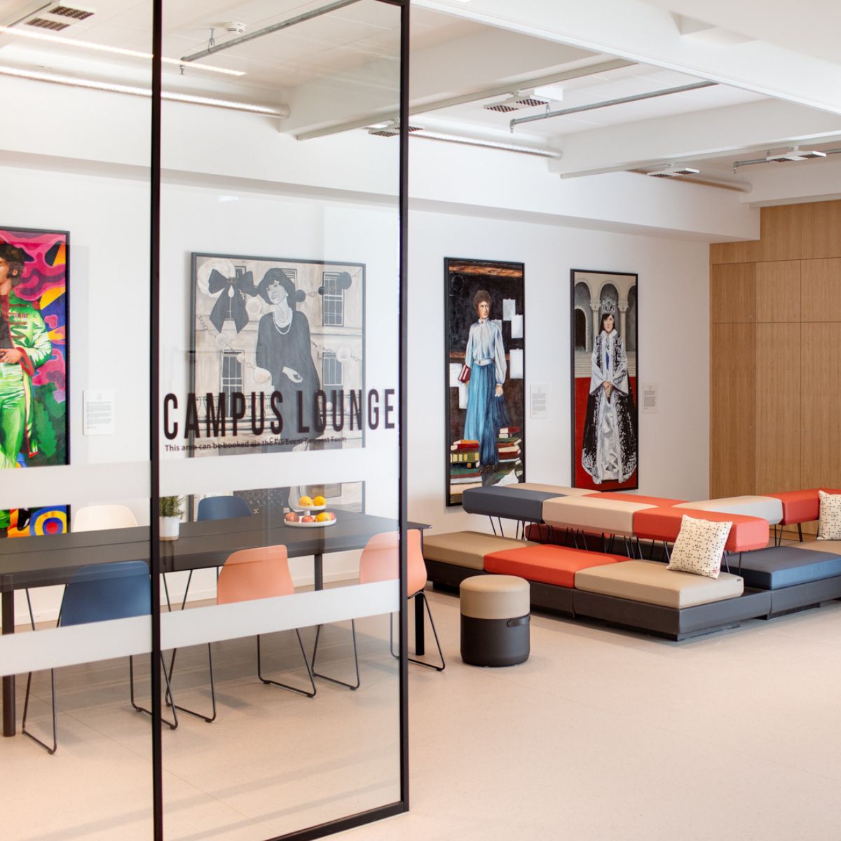 Campuslounge mit Gemälden und Sitzgelegenheiten in der Cafeteria der Frankfurt International School, geplant und eingerichtet von designfunktion
