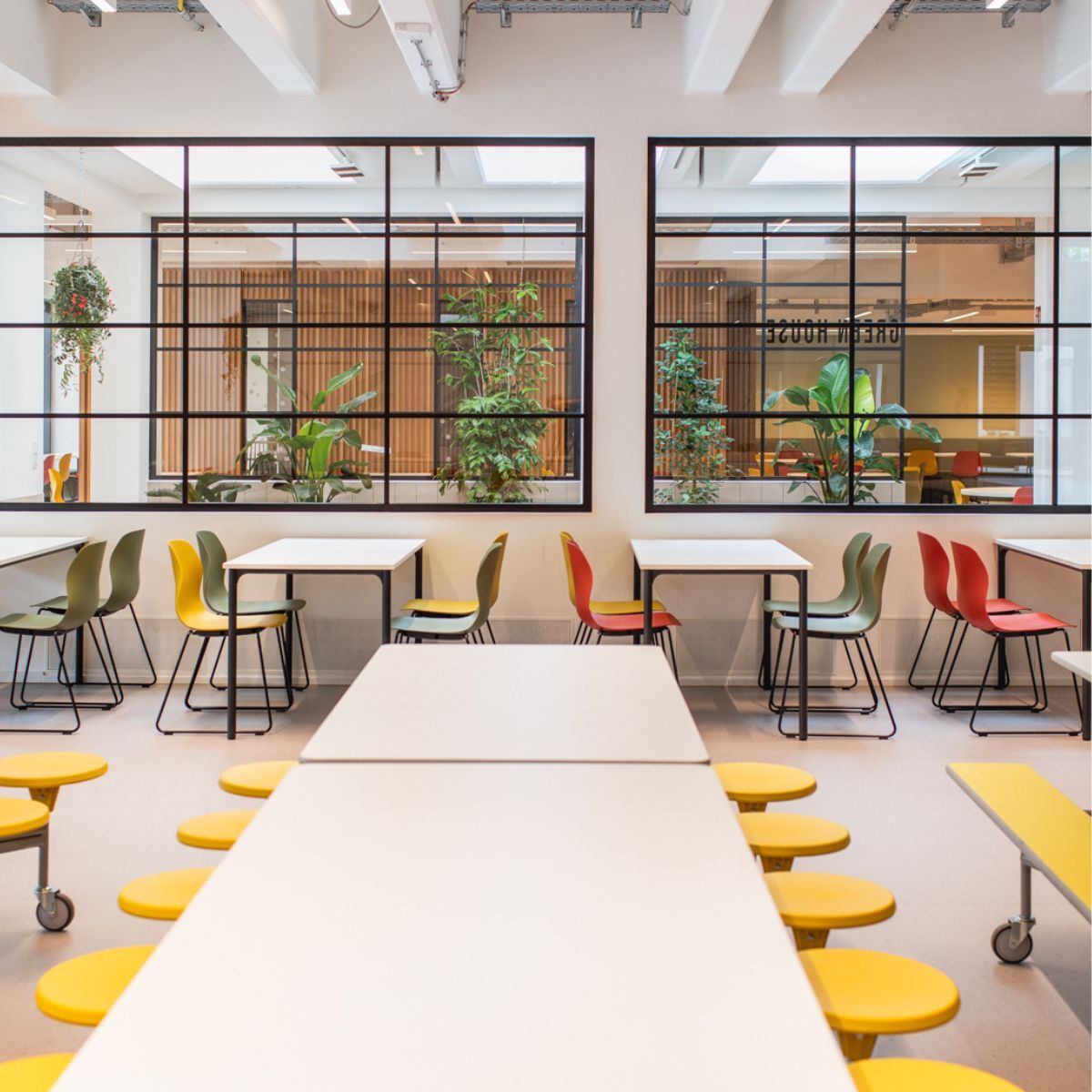 langer mobiler Tisch mit Sitzhockern in der Cafeteria der Frankfurt International School, geplant und eingerichtet von designfunktion