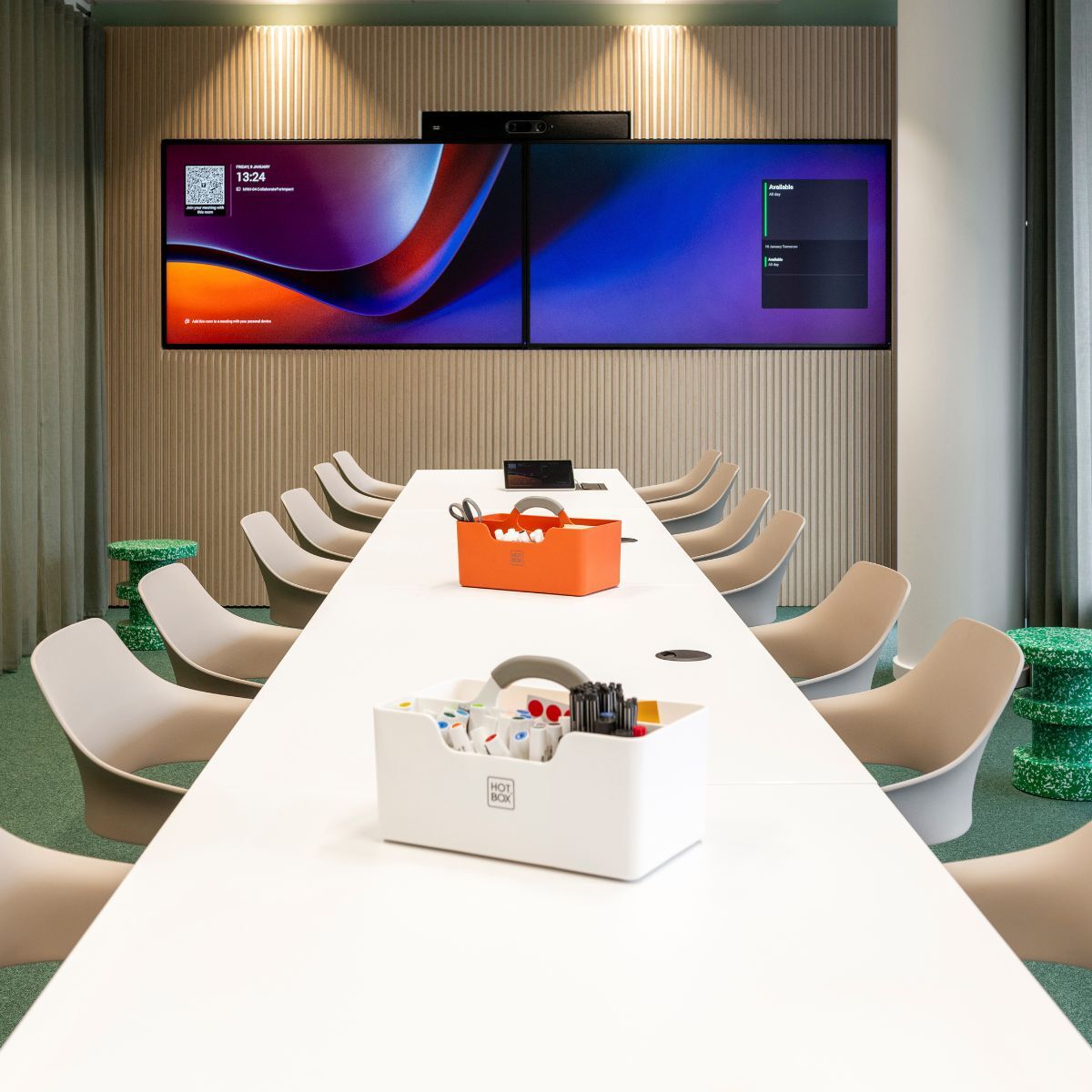 Meetingraum mit großen Bildschirmen, langem Tisch und Stühlen bei der Haleon Germany GmbH, geplant und eingerichtet von designfunktion