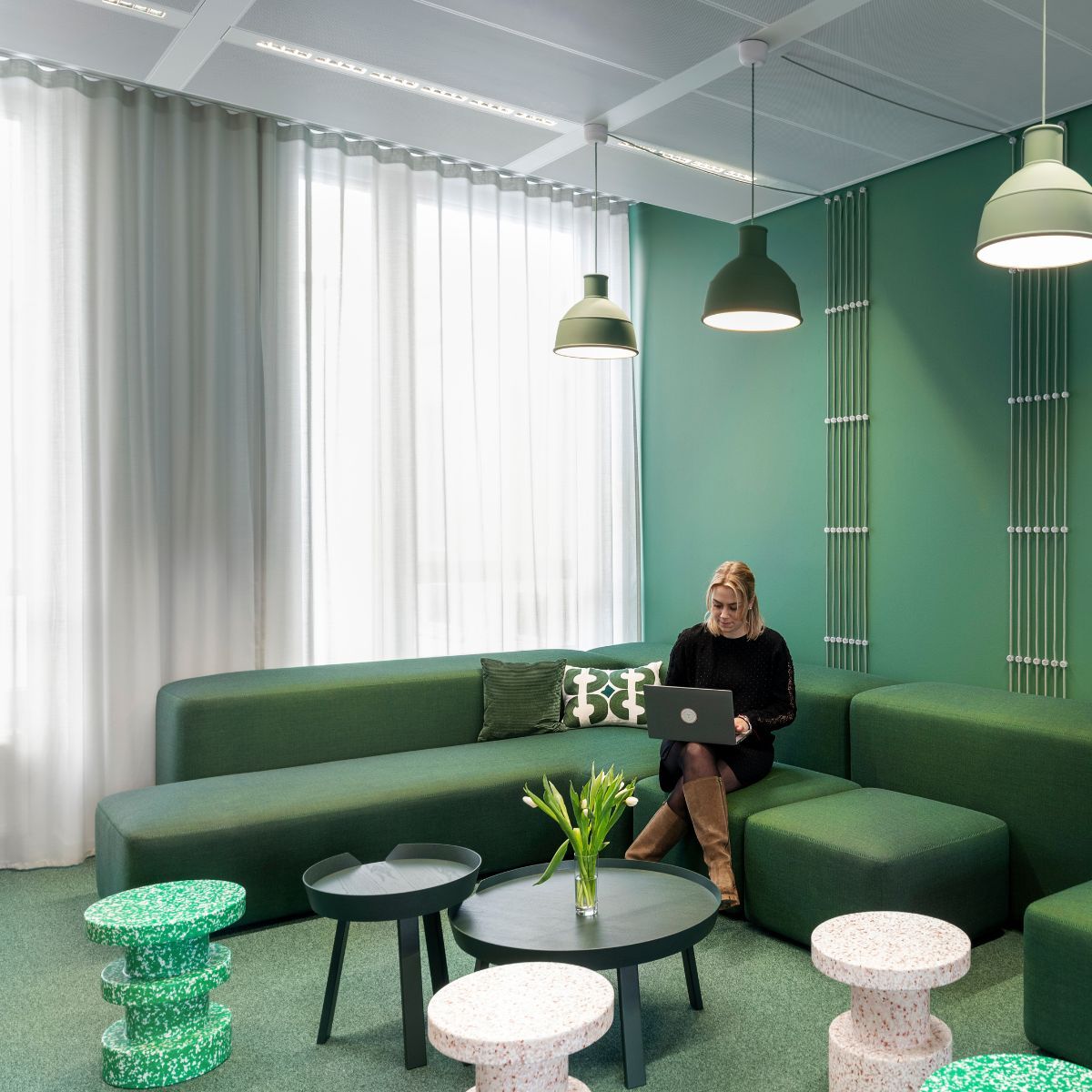 Mitarbeiterin mit Laptop im Social Space der Arbeitswelt der Haleon Germany GmbH, geplant und eingerichtet von designfunktion