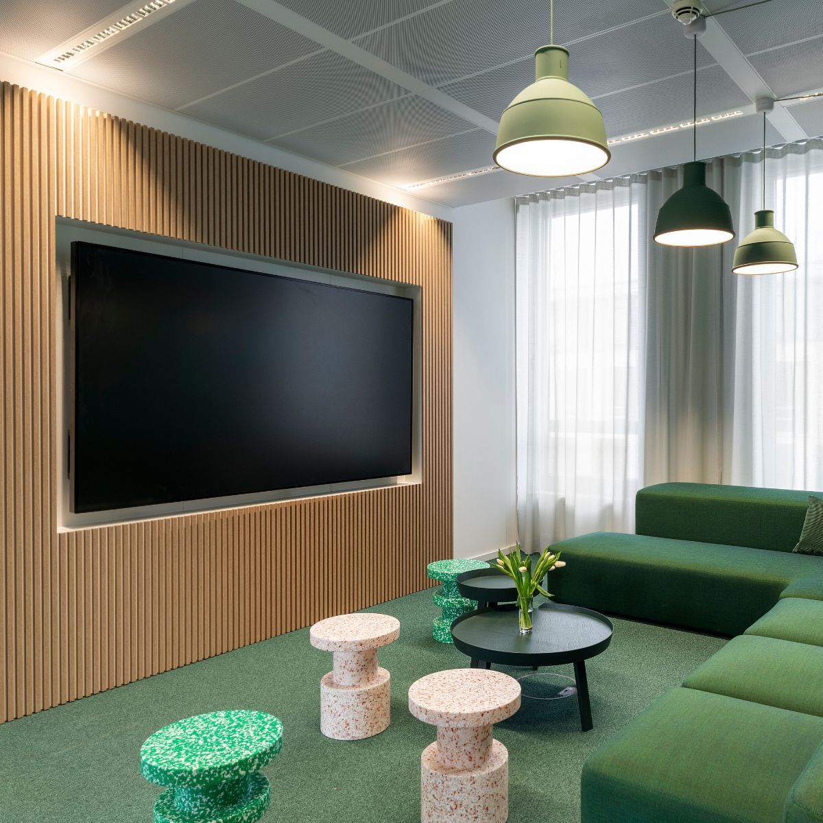 Coworking-Bereich mit großem Bildschirm, Sofa und flexibel einsetzbaren Sitzmöbeln bei der Haleon Germany GmbH, geplant und eingerichtet von designfunktion