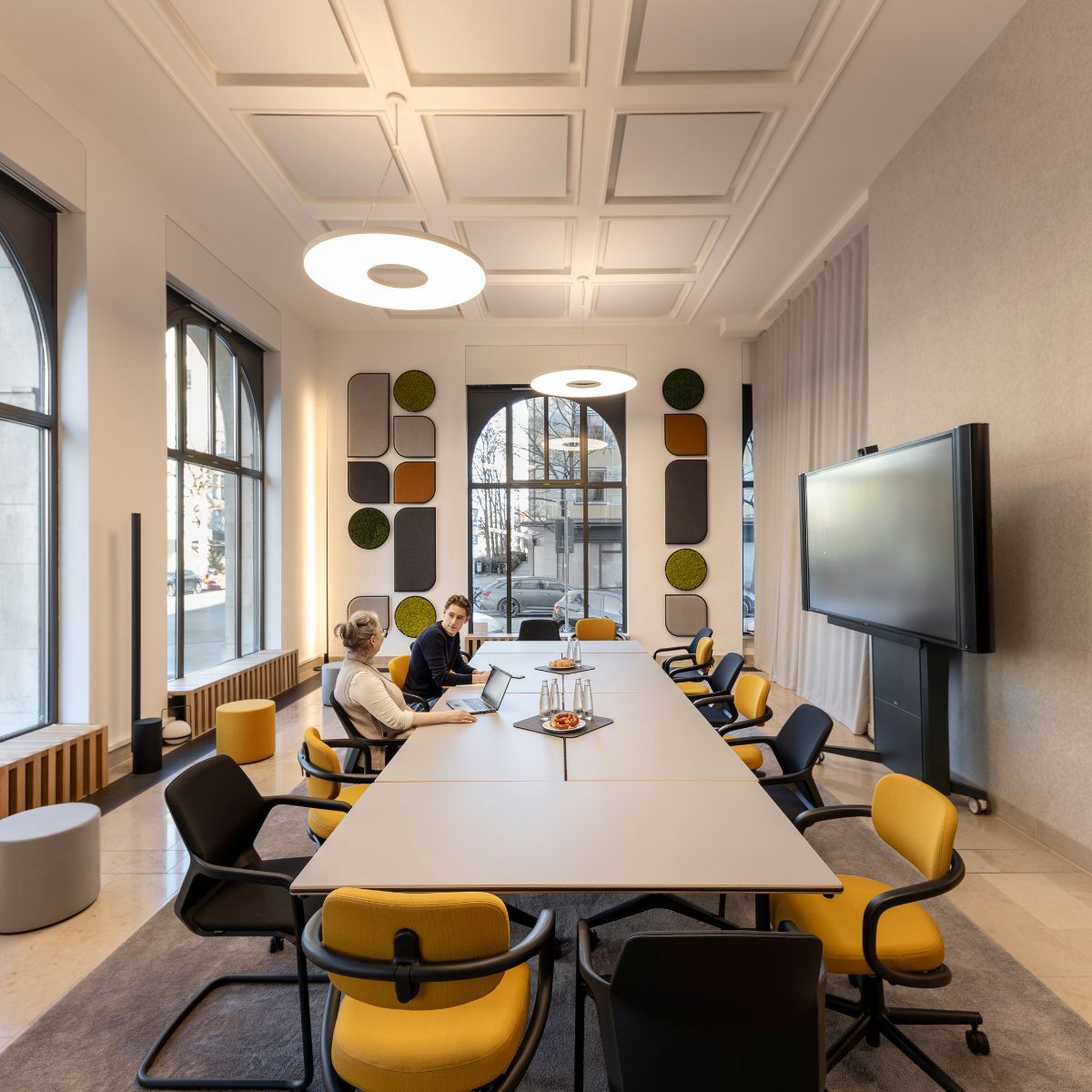 zwei Personen im Gespräch am großen Besprechungstisch im Co-Working Bereich der IHK München und Oberbayern, geplant und eingerichtet von designfunktion