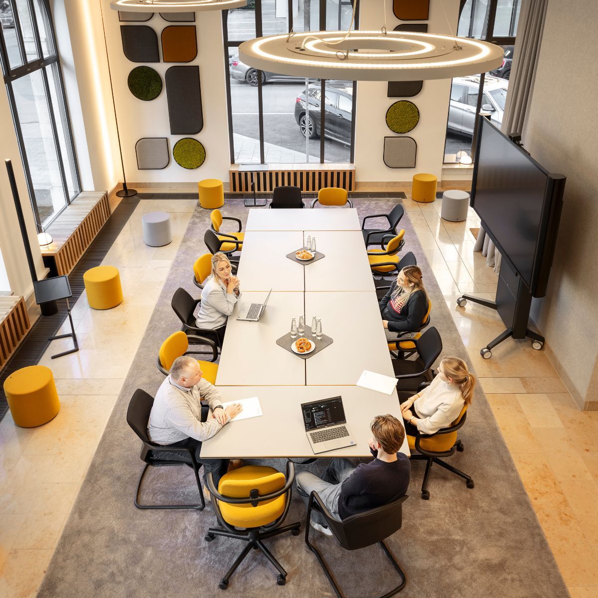 Menschen am großen Meetingtisch im Co-Working Bereich der IHK München und Oberbayern, geplant und eingerichtet von designfunktion