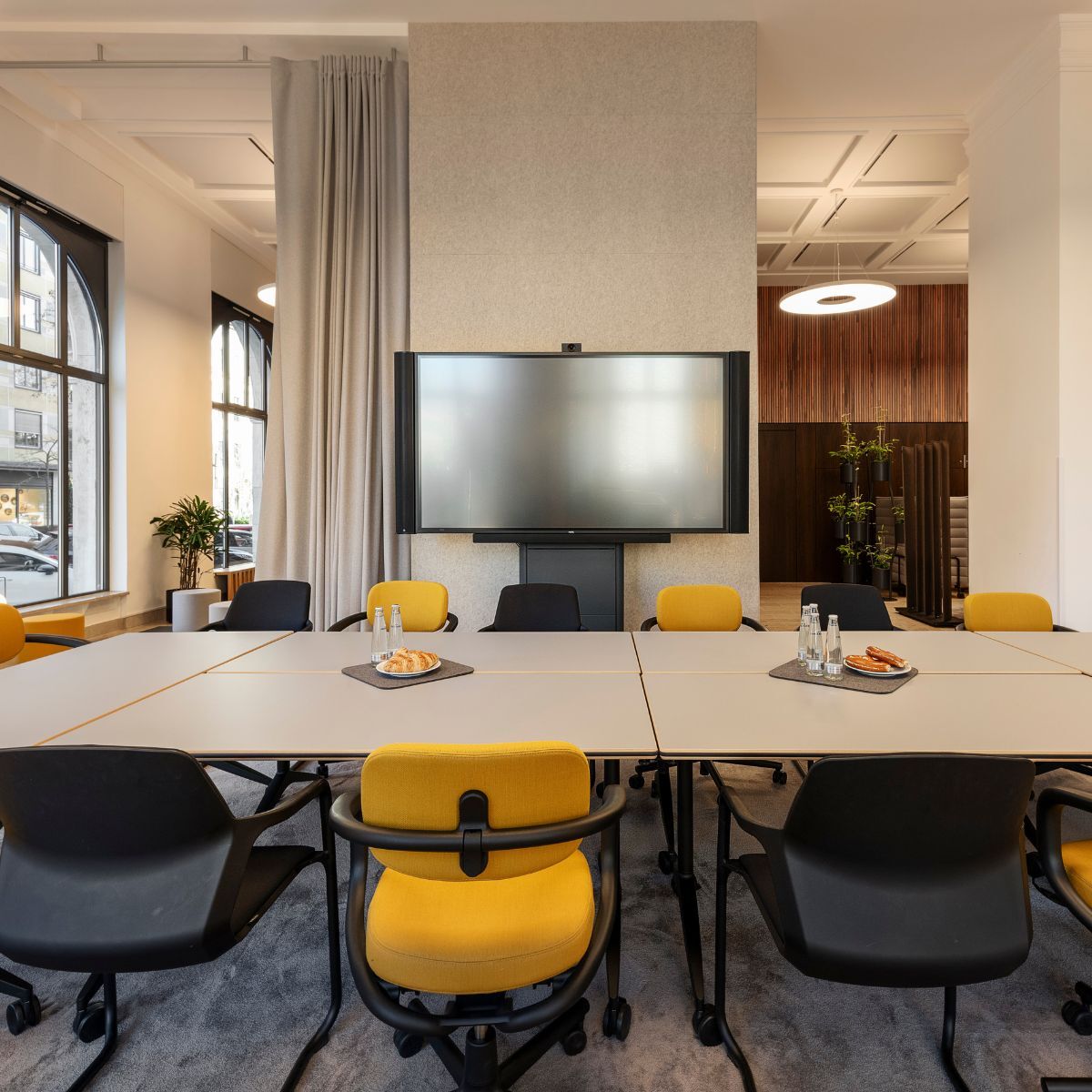 großer Besprechungstisch mit Bildschirm im Co-Working Bereich der IHK München und Oberbayern, geplant und eingerichtet von designfunktion