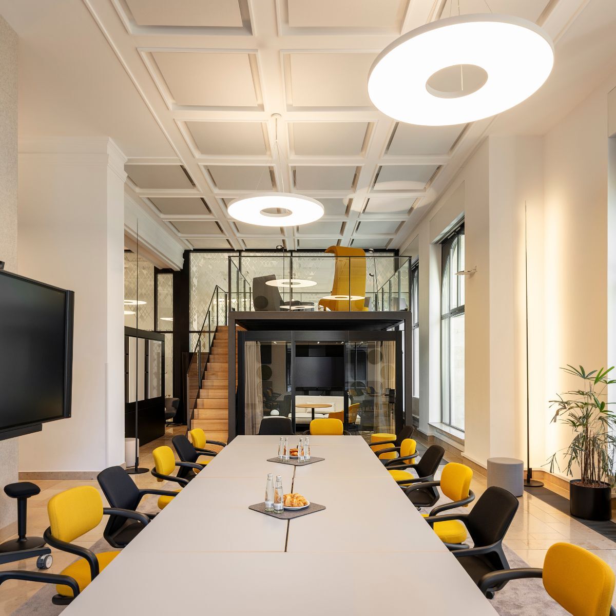 Blick über langen Konferenztisch mit angrenzendem Raum-in-Raum-System und Galerie im Co-Working Bereich der IHK München und Oberbayern, geplant und eingerichtet von designfunktion