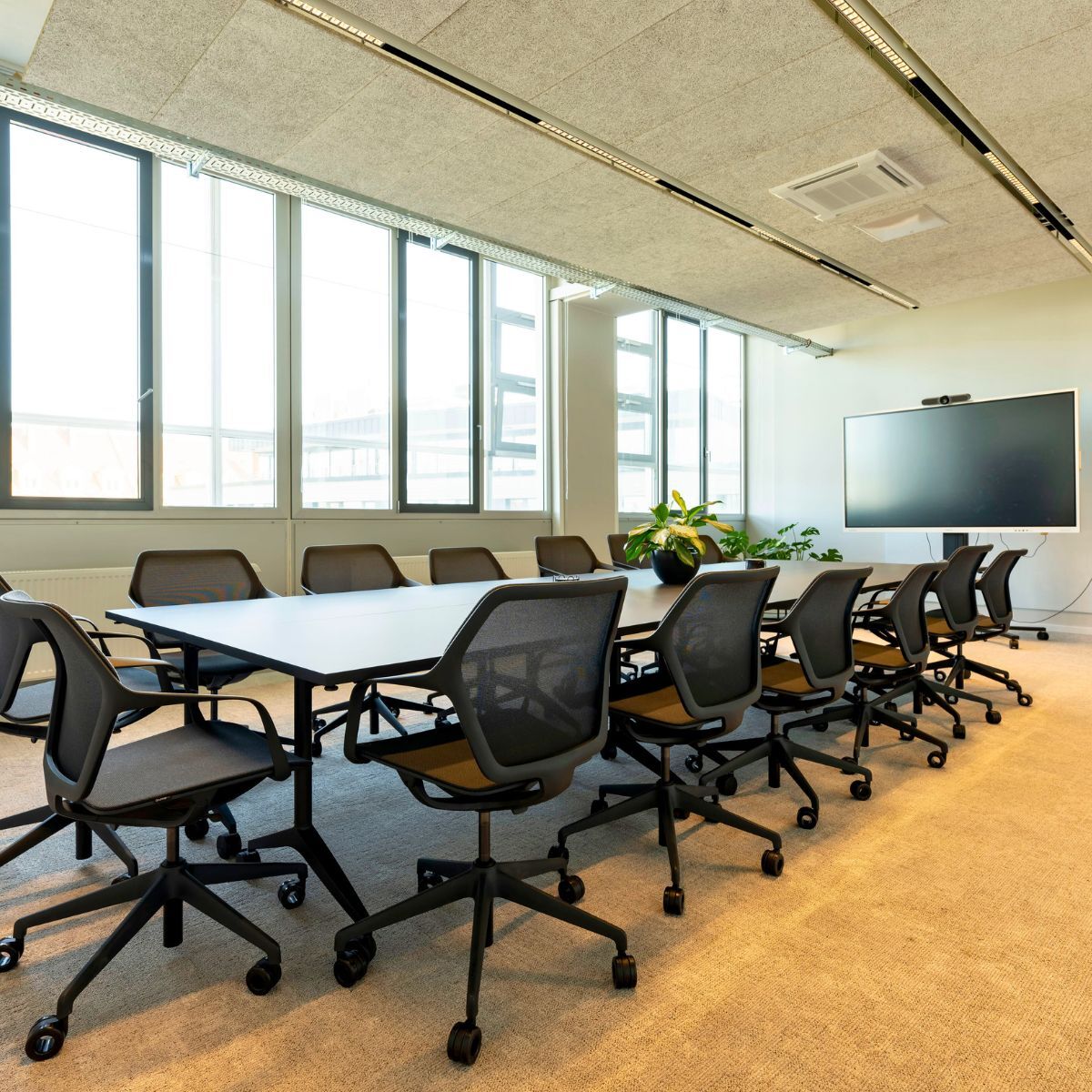 Meetingraum mit langem Tisch, Stühlen und Bildschirm im Headquarter von Proxima Fusion, konzipiert und eingerichtet von designfunktion