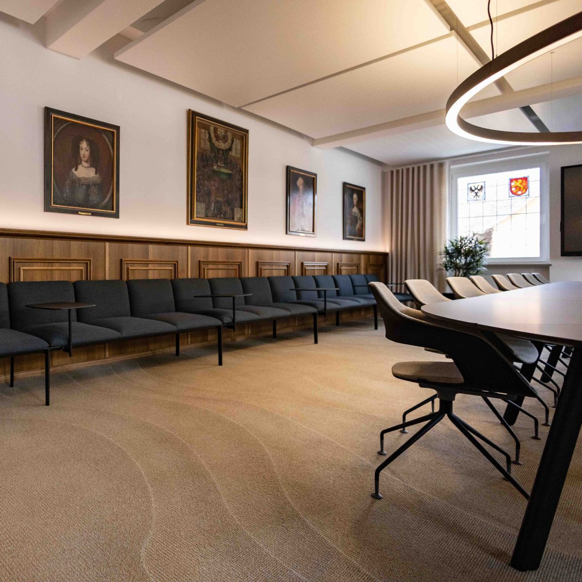 lange gepolsterte Sitzbank und historische Gemälde im Ratssaal der Stadt Aach, geplant und eingerichtet von designfunktion
