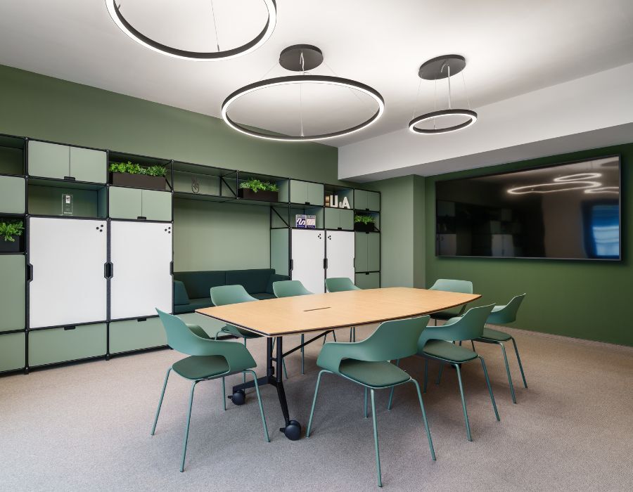 Meetingbereich mit Tisch und großem Bildschirm in der neuen Arbeitswelt von Virtimo, geplant und eingerichtet von designfunktion