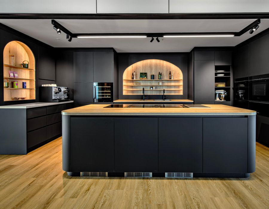 Show-Kueche mit schwarzen Fronten und Holz-Arbeitsflaeche in einem Buero