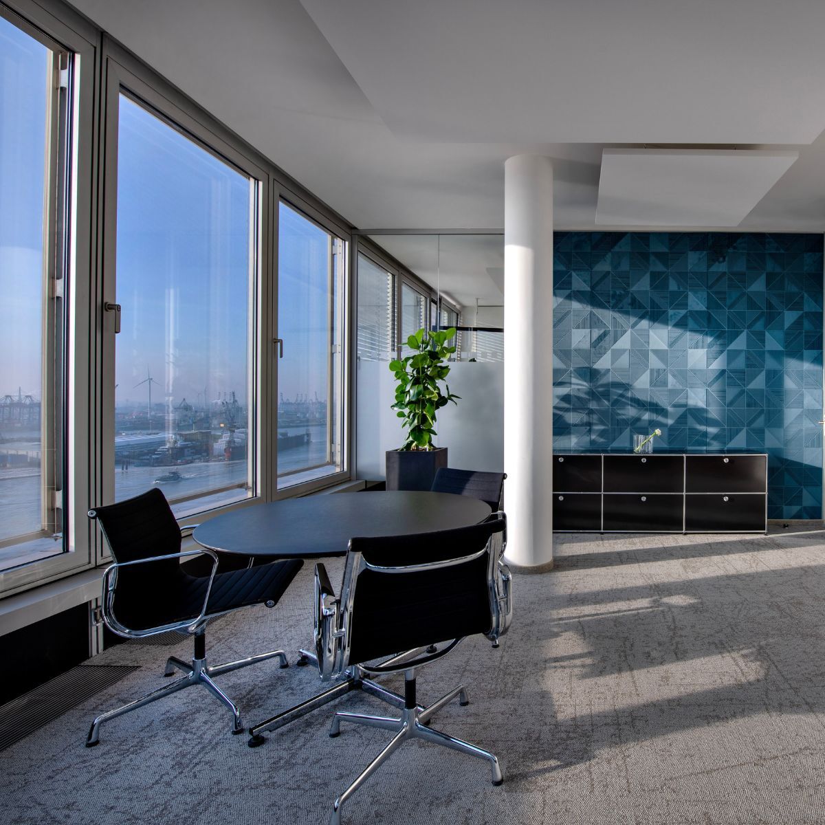 Minimalistisches Buero mit schwarzen Stuehlen und Tisch