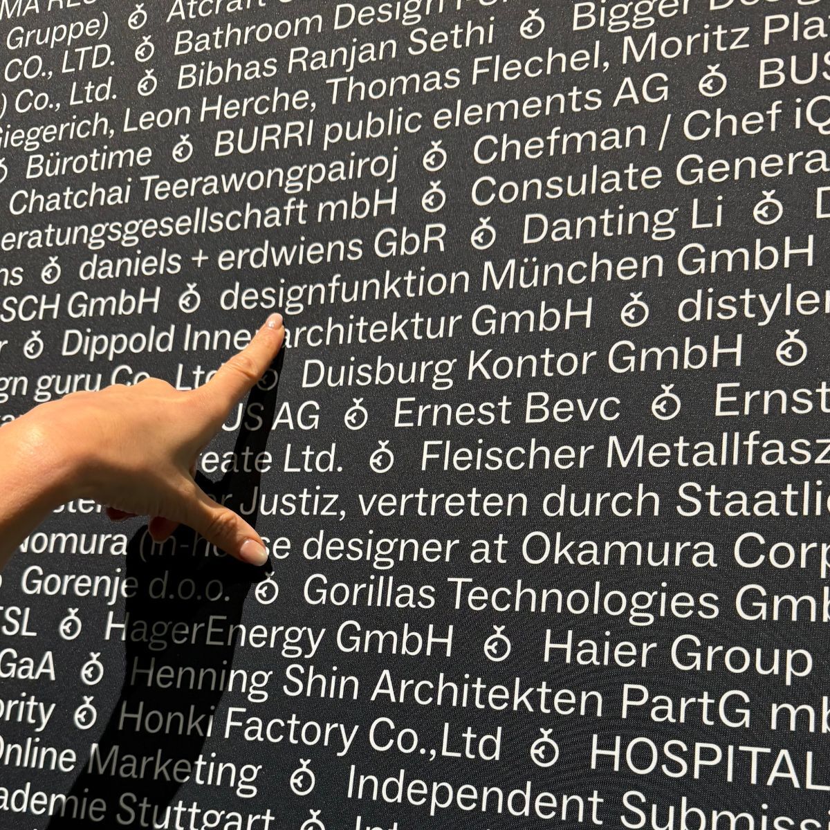 Hand, die auf der Wand mit den Namen aller Preisträger des German Design Awards 2026 auf designfunktion München zeigt
